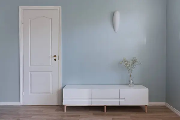 客厅的家具在地板上 蓝色的空墙和白色的门前面 花瓶中的家居装饰 上方的灯 — 图库照片