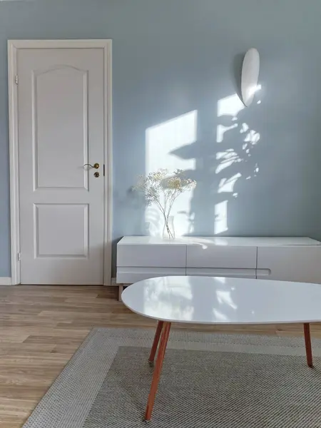 客厅的家具 咖啡桌和电视机站在蓝色的空墙和白色的门前面 在花瓶 阳光和阴影中装饰家 免版税图库照片