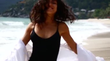 Genç esmer kadın tropik bir sahilde dans ediyor..
