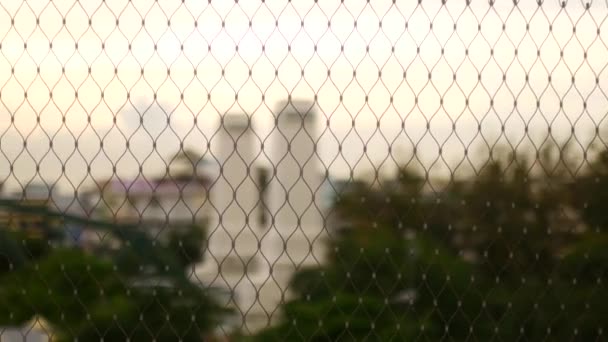 市内のメッシュフェンス 背景の建物のぼやけたシルエット — ストック動画