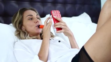 Yatakta telefon ve tüple genç bir kız..