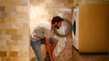 Adamın biri çamaşır makinesine bir şeyler atıp çalıştırıyor..