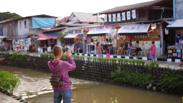 街中で川を撮る若い女性 — ストック動画