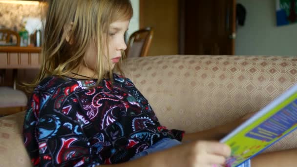 Rapariga Está Ler Livro Sofá Criança Está Aprendendo Ler — Vídeo de Stock