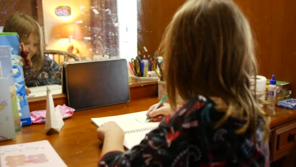 女の子は宿題をする 学生は机の上に座っている間にノートブックに書き込みます — ストック動画