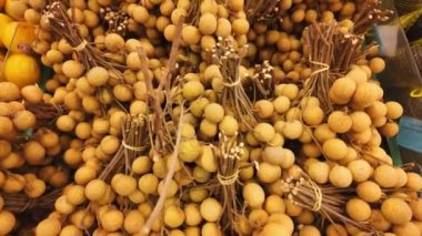 Dallardan sarkan longan meyveleri, şeffaf ve sulu iyiliklerinin yakın bir görüntüsünü sunuyor. Tropikal meyveler, egzotik hasatlar veya benzersiz mutfak içeriği
