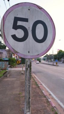 Bir yol kenarına yerleştirilmiş 50 numaralı hız limiti işaretinin çeşitli çekimlerini gösteren bir video. Araba sürerken hız limitlerine bağlı kalmanın önemini vurgulamak