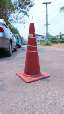 Yol kenarı işareti olarak yerleştirilmiş kırmızı bir trafik konisi ile yol güvenliği tedbirlerini vurgula, trafik akışını etkin bir şekilde tanımla ve yol güvenliğini arttırmak için kontrol et.