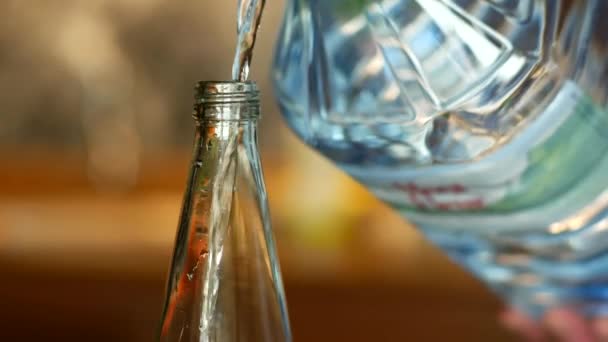 大きなジャグから洗練されたガラス瓶に水を移すプロセスは 外出先で利便性と水分補給を示しています — ストック動画