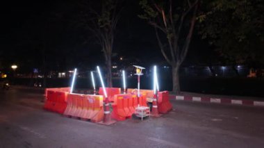 Bölge kırmızı bariyerlerle kordon altına alınırken ve gece bakımında güvenlik ve görünürlük sağlamak için sinyal lambalarıyla aydınlatılırken, gece yol onarımı sahnesi. İnşaat için ideal