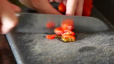 Taze vişneli domatesler bıçak ile ustalıkla dilimlenir. Salata hazırlama ve yemek pişirme dersleri için birebirdir.