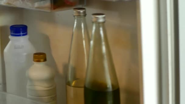 当冷藏柜的门打开时 你可以看到里面藏着各种各样的饮料 一只手伸出手去抓起一个冰凉的瓶子 展示了喝冷饮的便利性 — 图库视频影像