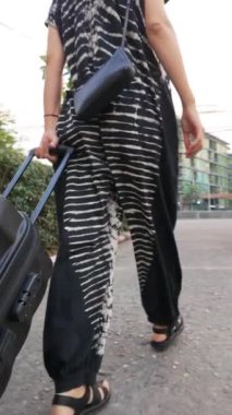 modern woman as she effortlessly rolls her suitcase, epitomizing contemporary travel with seamless movement and convenience