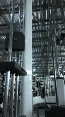 Spor yaparken hareket eden bir spor makinesinin ağırlıklarının yakın çekimi. Beden eğitimi, spor aletleri işlevselliği ve egzersiz rutinleri için ideal.