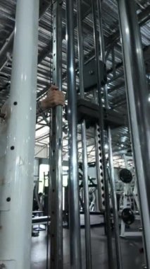 Spor yaparken hareket eden bir spor makinesinin ağırlıklarının yakın çekimi. Beden eğitimi, spor aletleri işlevselliği ve egzersiz rutinleri için ideal.