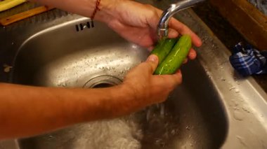 Bir adam köy mutfağında sebze yıkıyor. Yüzü olmadan yakın plan.