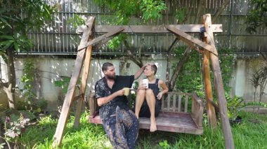 Genç bir çift arka bahçedeki bir salıncakta çıplak ayakla oturmuş sıcak kahveyi yudumluyor ve bağlantı anlarını paylaşıyor. Etrafları yemyeşil ve sabah ışığıyla çevrili, konuşuyorlar, sarılıyorlar ve...