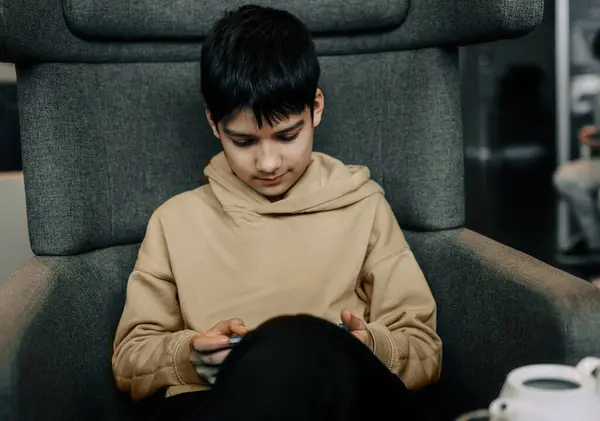 Ένα Νεαρό Αγόρι Κάθεται Μια Αίθουσα Αναμονής Καφέ Απορροφημένο Παίζει Εικόνα Αρχείου