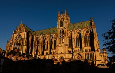 Sıcak akşam güneşi altında Gotik bir katedral. Açık mavi gökyüzünün altında karmaşık mimari yapılar ve yüksek kuleler var.