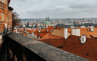 Kırmızı çatıları ve bulutlu gökyüzünün altında yeşil kubbeli kilisesi olan tarihi Avrupa şehrinin manzarası