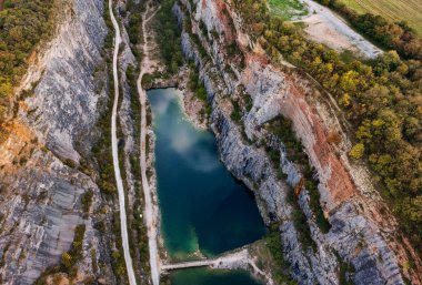 Derin zümrüt su gölü ve dik yamaçlı kayalık kanyon manzarası.