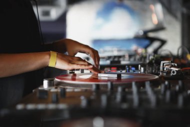 Bayan DJ, vinil plak çalar ve ses mikseriyle birlikte sette. Profesyonel kulüp disk jokeyi sahnede müzik parçalarını karıştırıyor
