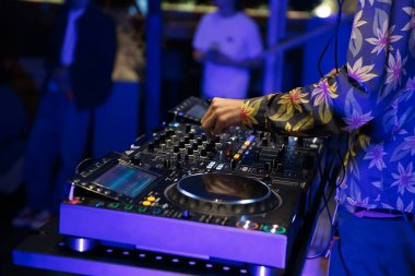 Parti DJ 'i tekno müziği modern CD pikaplarıyla ve dört kanal ses mikseriyle karıştırıyor. Gece kulübünde kulüp diskjokeyi oynuyor.