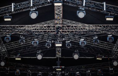 Concert stage lighting mounted on high rack. Professional music festival lights installed on stadim scene clipart