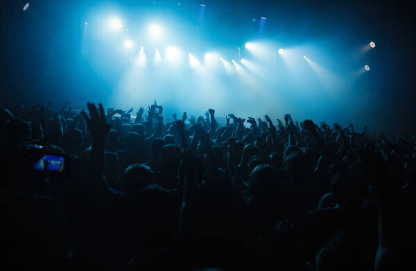 Концертная толпа бредит под музыку. Большая группа молодых людей веселится на музыкальном фестивале в ночном клубе