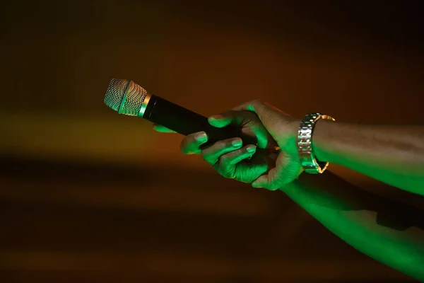 Rap singer with mic in hand. Black rapper performing on concert with wireless microphone