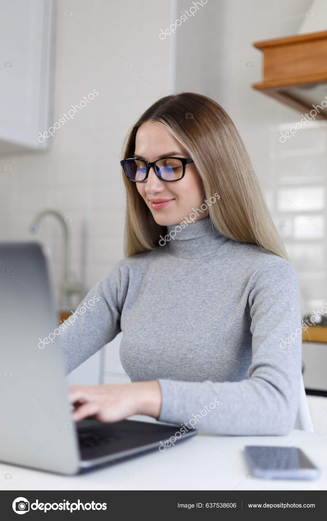 Young blonde woman browsing internet on tablet computer device at home.  Beautiful white female wearing nerd glasses and grey turtleneck shirt using  modern gadget for online communication Stock Photo