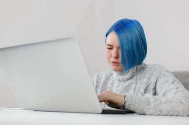 Focused millennial woman typing text on notebook keyboard. Freelancer female person works on modern laptop computer at home