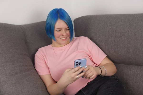 Cheerful Blue Haired Female Person Lying Couch Browsing Social Media — Zdjęcie stockowe