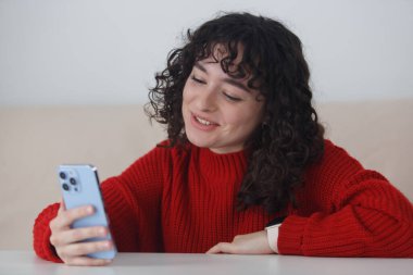 Friendly white girl talking on frontal camera of a smart phone. Cheerful young adult female speaking on video call