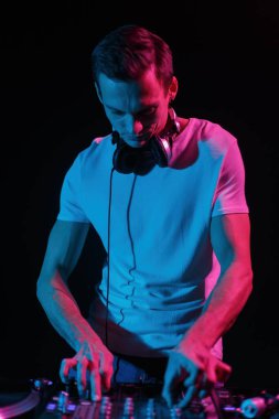 Cool young DJ playing music in night club. Young white man mixing musical tracks with sound mixer on techno party