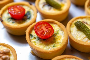 Delicious canape with cheese and cherry tomatoes baked in restaurant kitchen. Wine party appetizer dish in close up