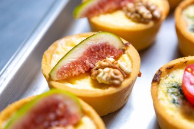 Delicious canape with fresh figs, walnut and melted cheese. Groupd of gourmet snacks for wine party being prepared in restautant kitchen