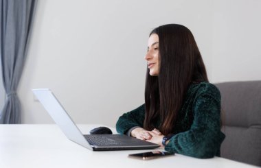 Friendly young woman speaking on laptop web camera. Cheerful white female person studying online with a notebook computer