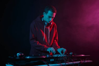 Cool young DJ plays music on party. Professional disk jockey mixing records. Hip hop disc jokey playing set with turntables