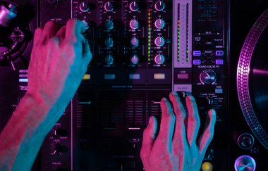 Club DJ mixing music with sound mixer device. Overhead photo of disc jockey playing set on party in night club
