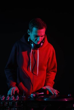 Club DJ scratching vinyl disc on turntable. Hip hop disc jockey scratches vinyls on record player in night club