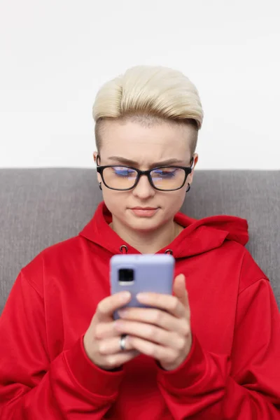Beautiful white woman person with short hair using mobile phone. Stylish tom boy female in glasses typing a message on smart phone