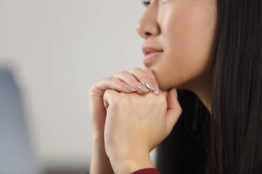Young BIPOC girl looking at computer in thought. Close up photo of unrecognizable Asian female person studying online with a laptop