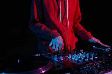 Hip hop dj scratches vinyl record on turntable. Disc jockey mixing musical tracks on turntables on party in night club