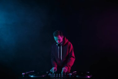 Hip hop dj plays set with vinyl records and sound mixer. Disc jockey playing music with turntables in night club