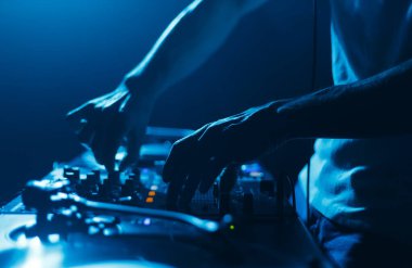 Hands of a DJ mixing music tracks with sound mixer. Close up photo of disc jockey playing set on stage in night club clipart