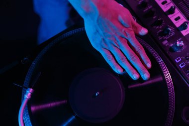 Hip hop dj scratching vinyl record on party in night club. Overhead photo of disc jockey mixing records 