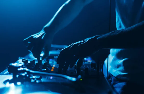 stock image Hands of a DJ mixing music tracks with sound mixer. Close up photo of disc jockey playing set on stage in night club