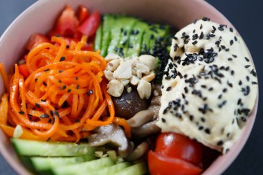Poke bowl with fresh ingredients. Delicious Hawaiian food prepared with natural products. Healthy lunch with hummus and raw vegetables