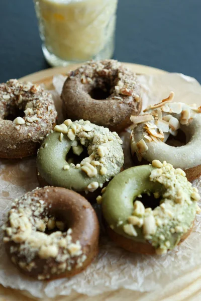 stock image Delicious fresh donuts covered with chocolate and nuts. Traditional Dutch olykoek doughnuts served on wooden plate for breakfast